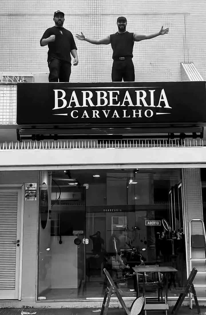 Fachada da Barbearia Carvalho na Rua Mariz e Barros, 490, com os fundadores sobre o letreiro